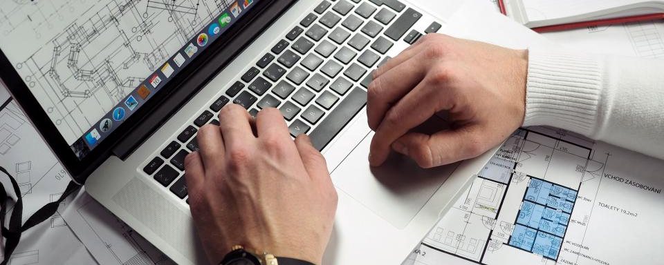 Laptop en schetsen van een werkproces op een bureau