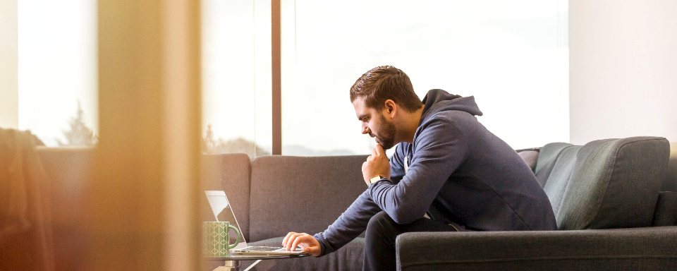Man denkt na op een bank bij het raam